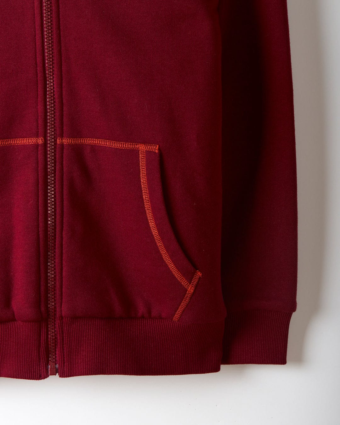 A close-up of the Depeche Kids Sherpa Lined Hoodie in red showcases its zipper, two front pockets with orange stitching, and subtle Saltrock branding.