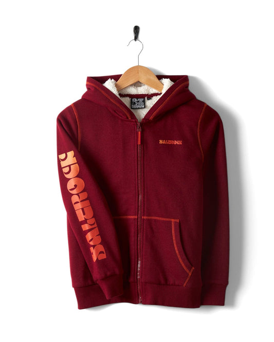 Red Saltrock Depeche kids Sherpa-lined hoodie with "Baleno" printed on the chest and sleeve, displayed on a wooden hanger.