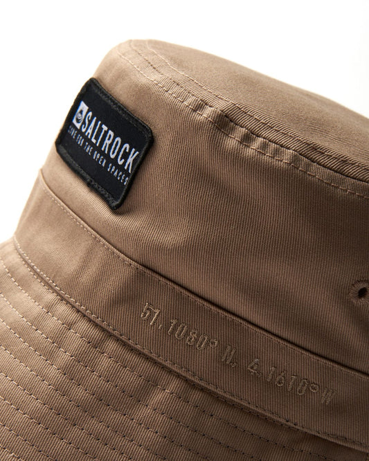 Close-up of a cream Dockyard bucket hat with a 'Saltrock badge' brand label, from North Devon.
