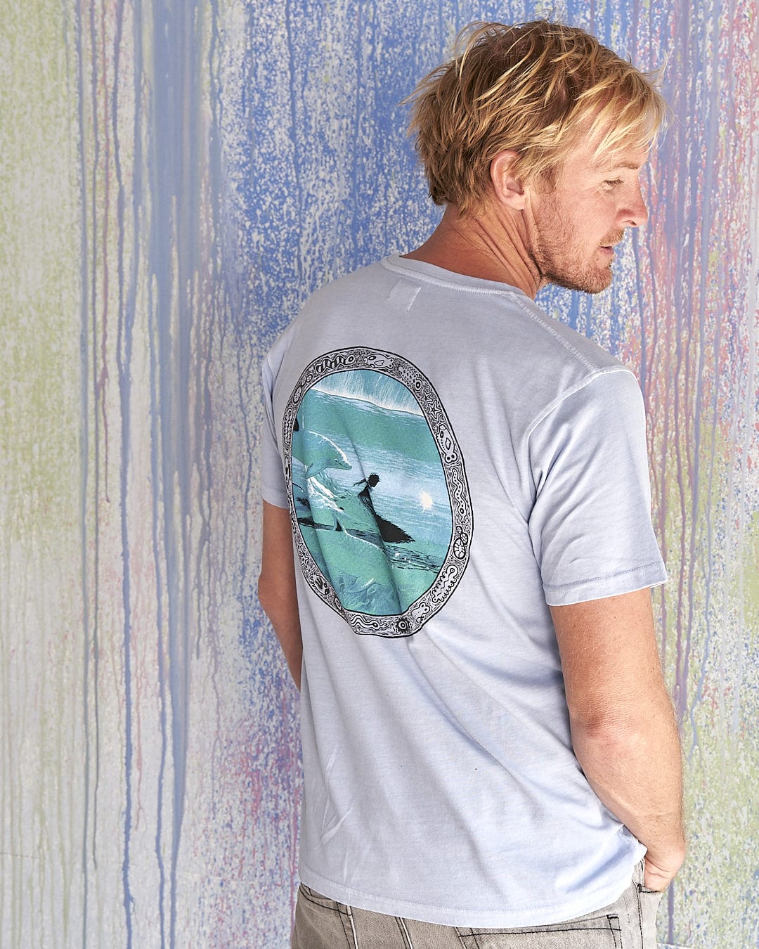 The back of a man wearing a Saltrock Dolphin - Limited Edition 35 Years T-Shirt.