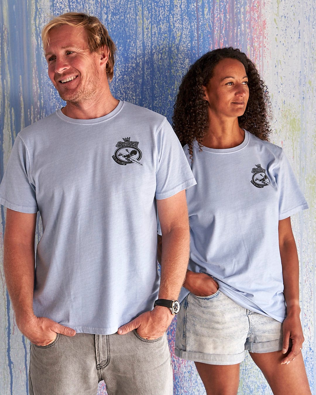 A man and woman standing next to each other wearing Saltrock's Dolphin - Limited Edition 35 Years T-Shirts.