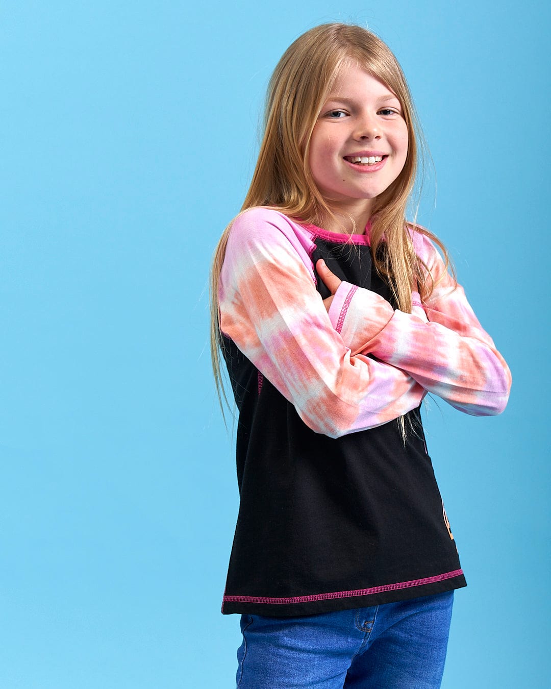 A little girl is posing for a photo in a Saltrock Elektra Tex - Kids Tie Dye Long Sleeve T-Shirt - Black.