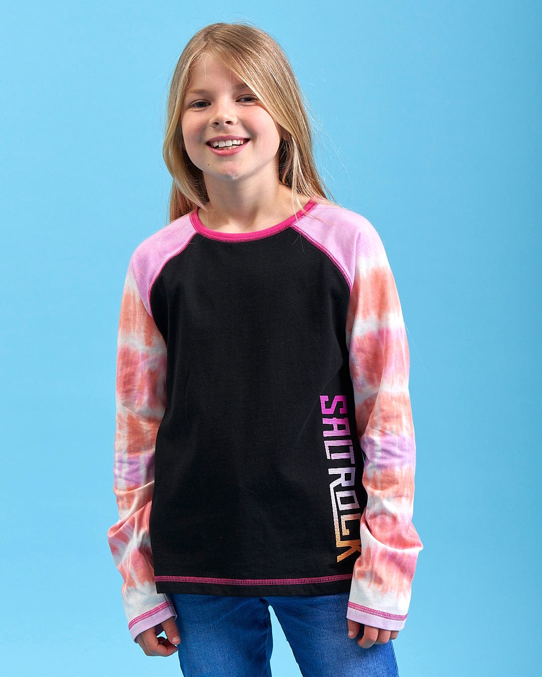 A young girl wearing an Elektra Tex - Kids Tie Dye Long Sleeve T-Shirt - Black by Saltrock.