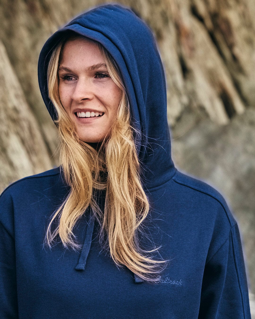 A woman stylishly dons a Saltrock Elsa - Womens Hooded Sweat Dress - Dark Blue, combining comfort and style effortlessly.