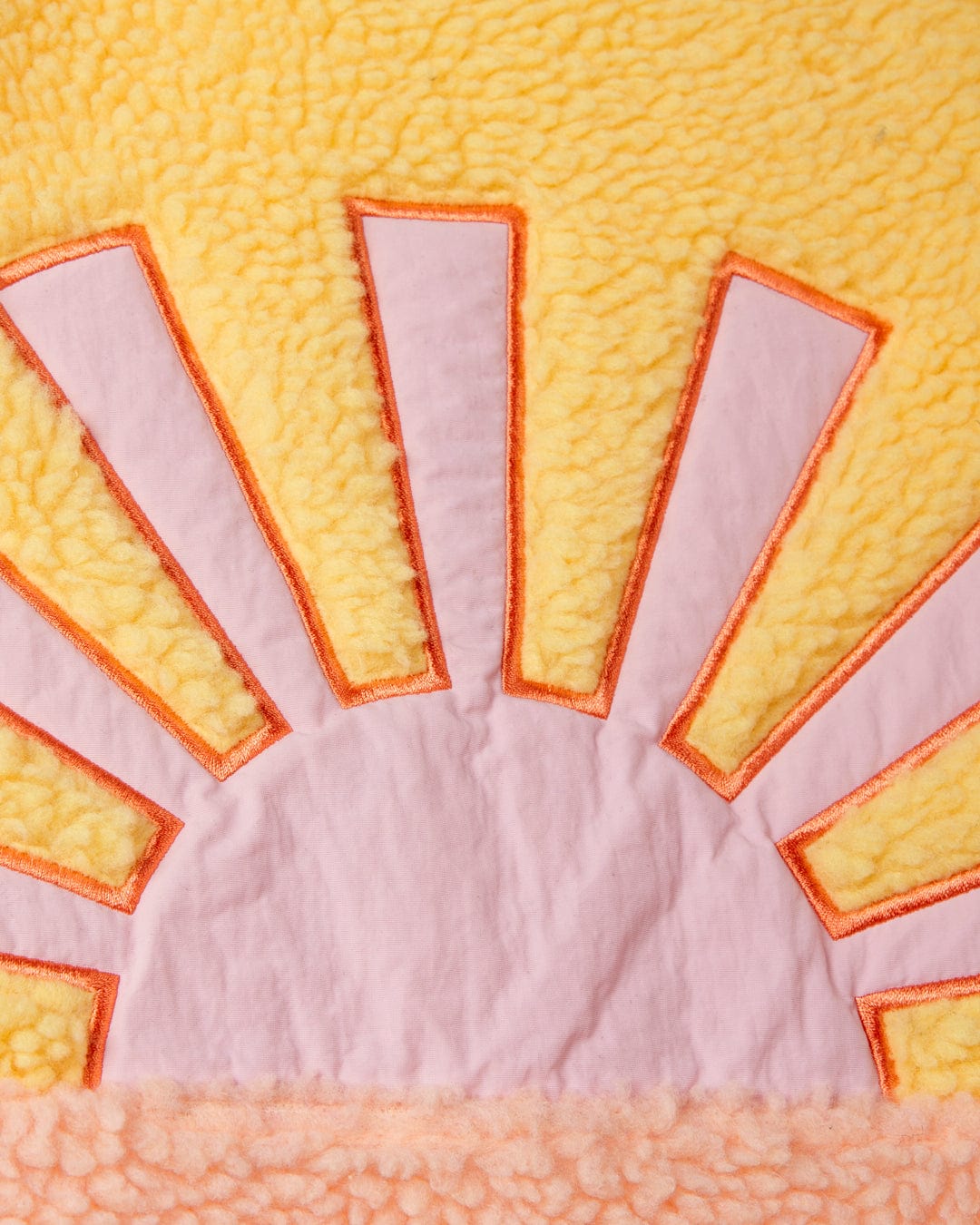 A close up of a Saltrock Emery Sunshine - Kids Sherpa Fleece - Yellow blanket with an embroidered sun graphic.