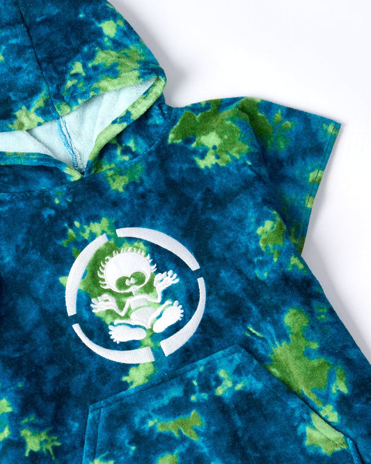 The Saltrock Fader Kids Changing Towel in green is crafted from ultra-absorbent, 100% cotton and features a blue and green tie-dye design with an embroidered alien-like character in a white circle on the chest.