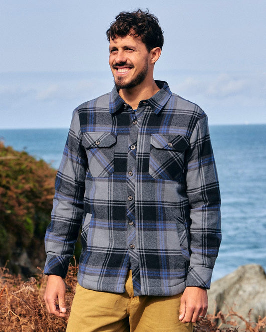 A man wearing a blue flannel shirt with versatile styling options replaced with "Woody - Mens Sherpa Lined Shacket - Grey" by Saltrock.