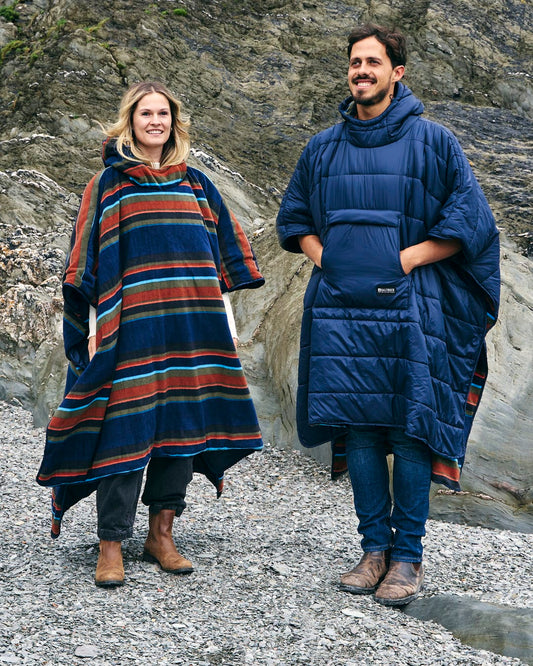 A man and a woman in a Saltrock Festival Reversible Poncho - Blue.