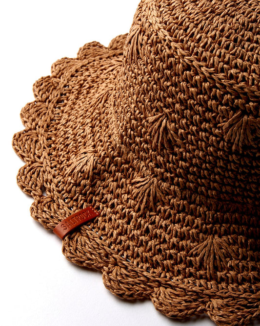 Close-up of a textured light brown woven Field straw bucket hat with a scalloped edge, a small Saltrock label, and a wire brim.