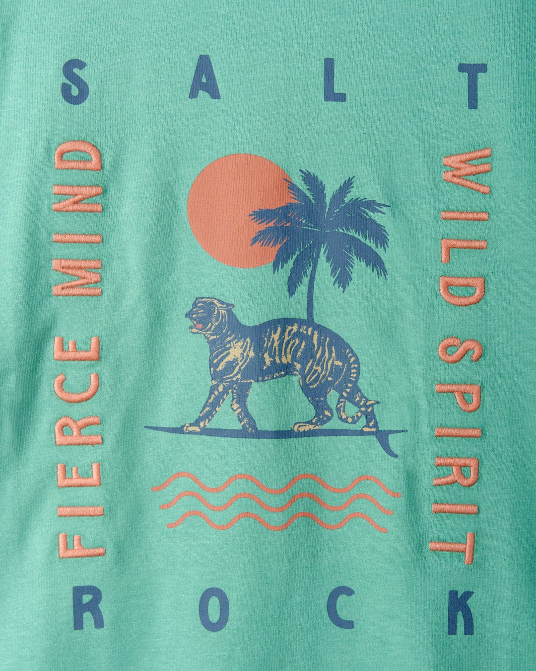 Graphic print of a tiger on a surfboard with palm trees, sun, and text elements on a Saltrock Fierce Mind cropped tee with a teal background.