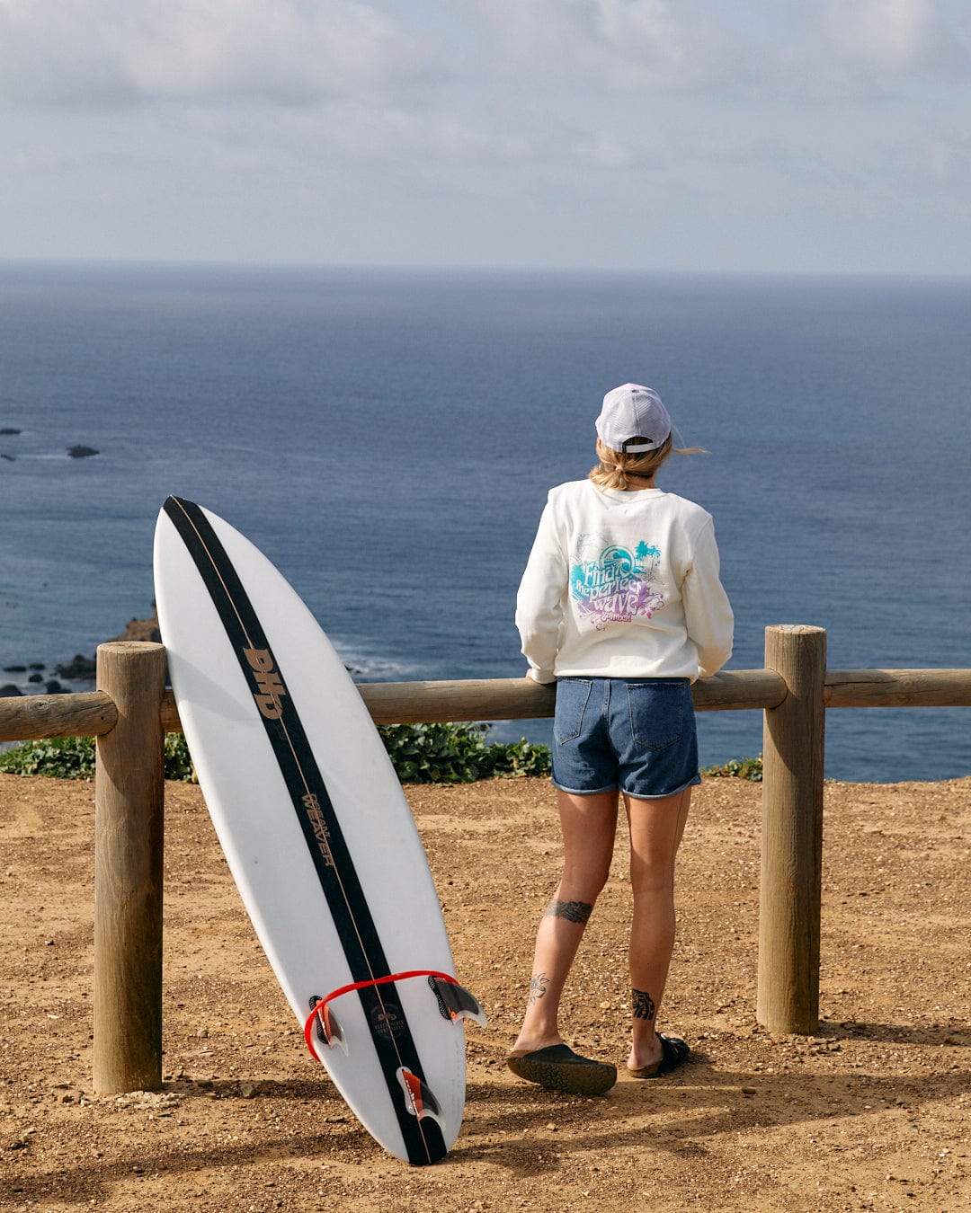 A woman with a Saltrock Find The Perfect Wave - Womens Sweat - White surfboard looking at the perfect wave.
