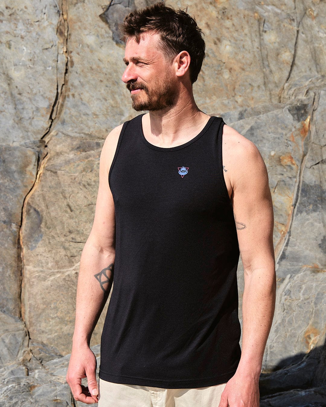 A man wearing a Saltrock Flame Tri - Mens Recycled Vest - Black tank top and tan shorts.