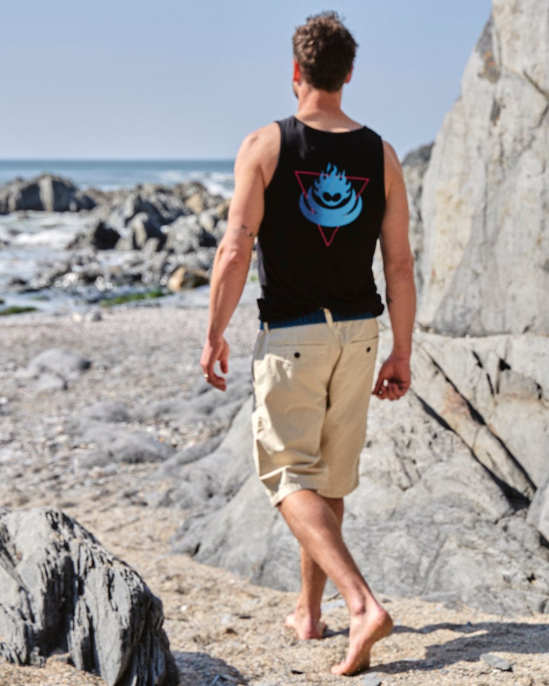 A man wearing a Saltrock Flame Tri - Mens Recycled Vest - Black walking along the beach.
