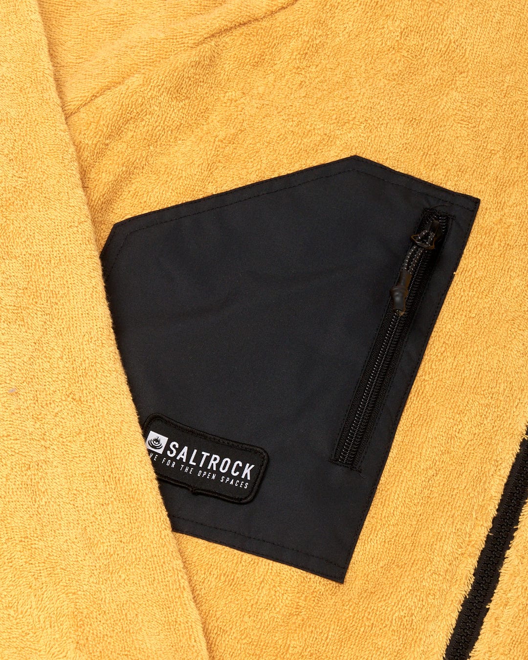 A Saltrock 3 in 1 Recycled Four Seasons Changing Robe in black and yellow, featuring a waterproof outer robe, a pocket with a zipper, lying on a yellow textured towel.