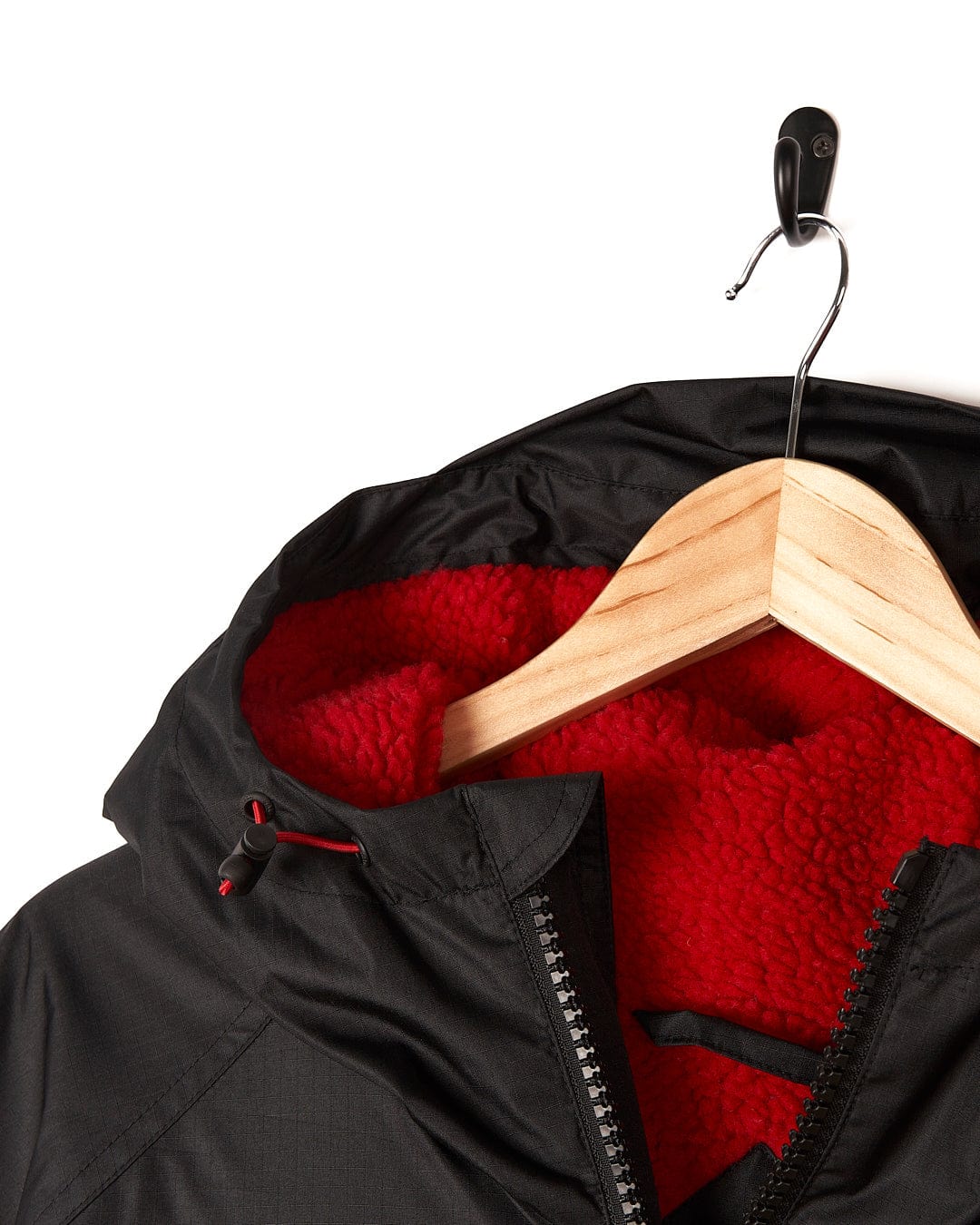 A Saltrock Four Seasons - Waterproof Changing Robe - Black/Red hanging on a wooden hanger.