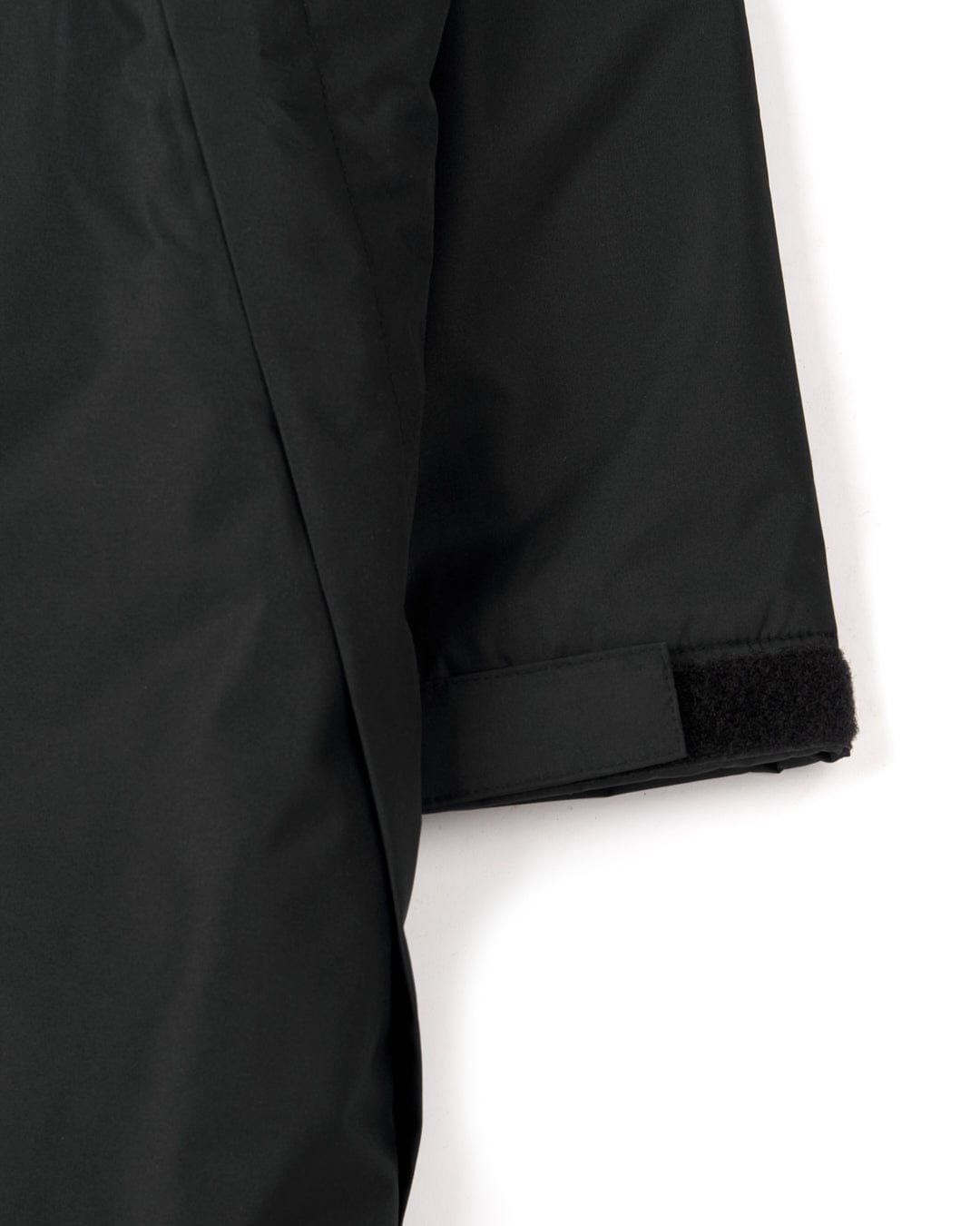 Close-up of a black jacket sleeve with a velcro strap at the cuff, crafted from recycled materials, on a white background. The product is called Recycled Kids Changing Robe - Black/Red by Saltrock.