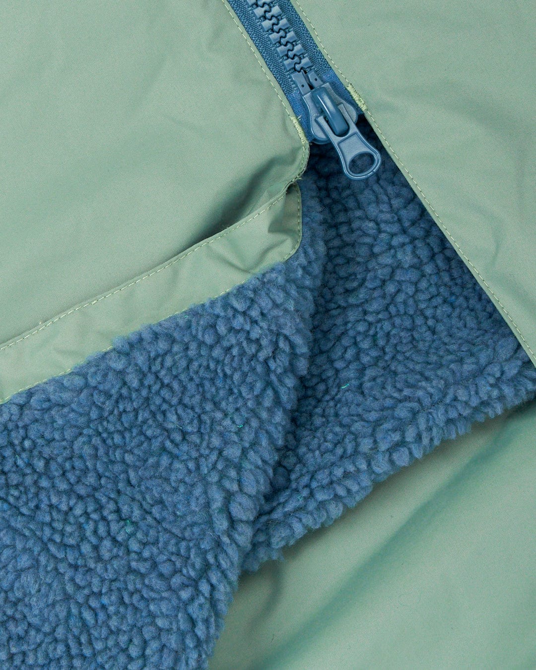 Close-up of a Saltrock Recycled Changing Robe - Light Green with an adjustable hood, featuring a blue zipper and blue fleece lining visible underneath.