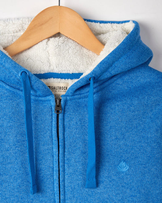 Close-up of a women's Saltrock Galak fur-lined hoodie in blue on a wooden hanger.