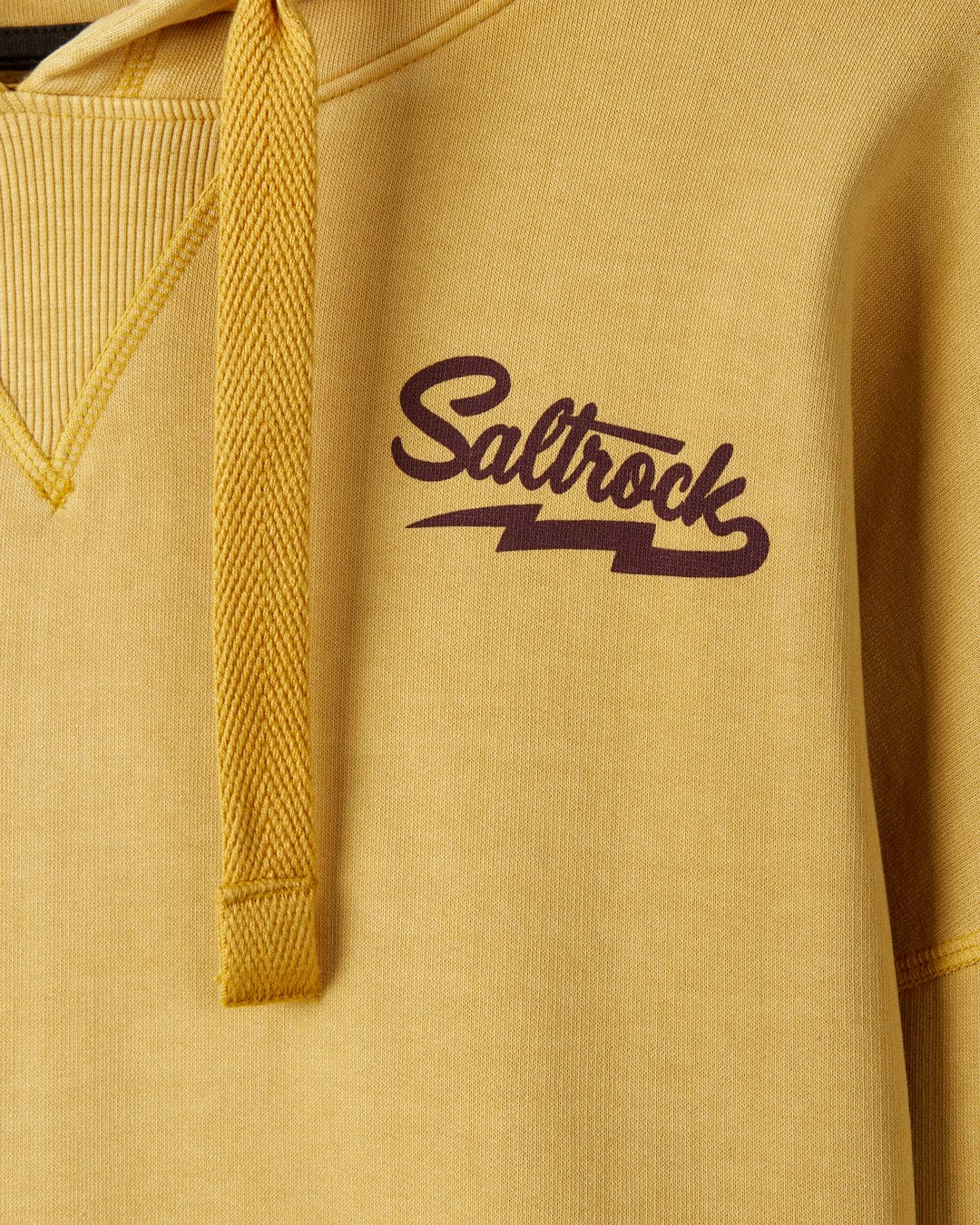 Close-up of a mustard yellow Saltrock Gas Station hoodie with a purple "Saltrock" logo, detailed texture on the drawstring, and fabric. This kangaroo pocket hoodie is crafted from recycled polyester.
