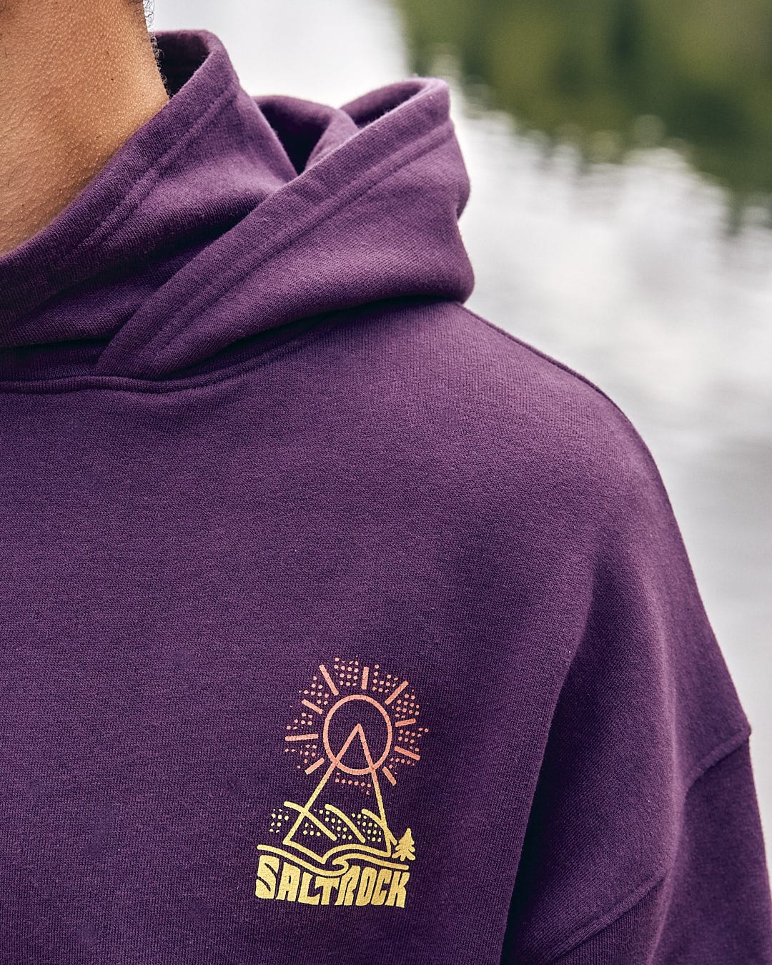 A man wearing a Saltrock Geo Peak - Mens Oversized Snood Pop Hoodie - Dark Purple with a mountain on it.