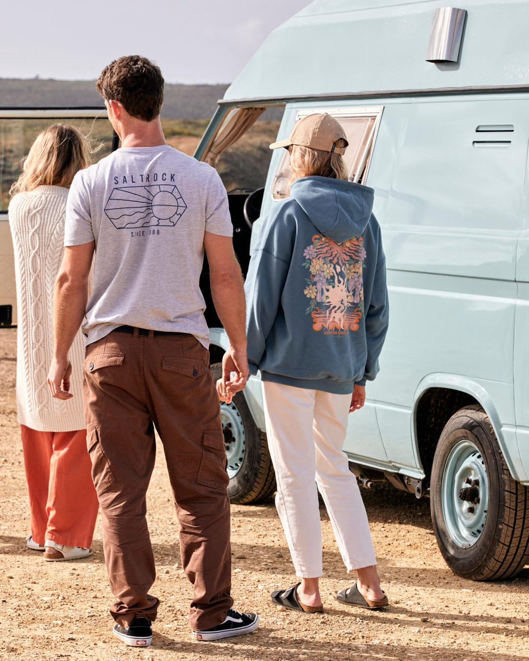 Three people standing next to a vintage van, dressed in casual attire with Saltrock branding, enjoying the outdoors in Godrevy 2 - Mens Cargo Trousers - Brown.