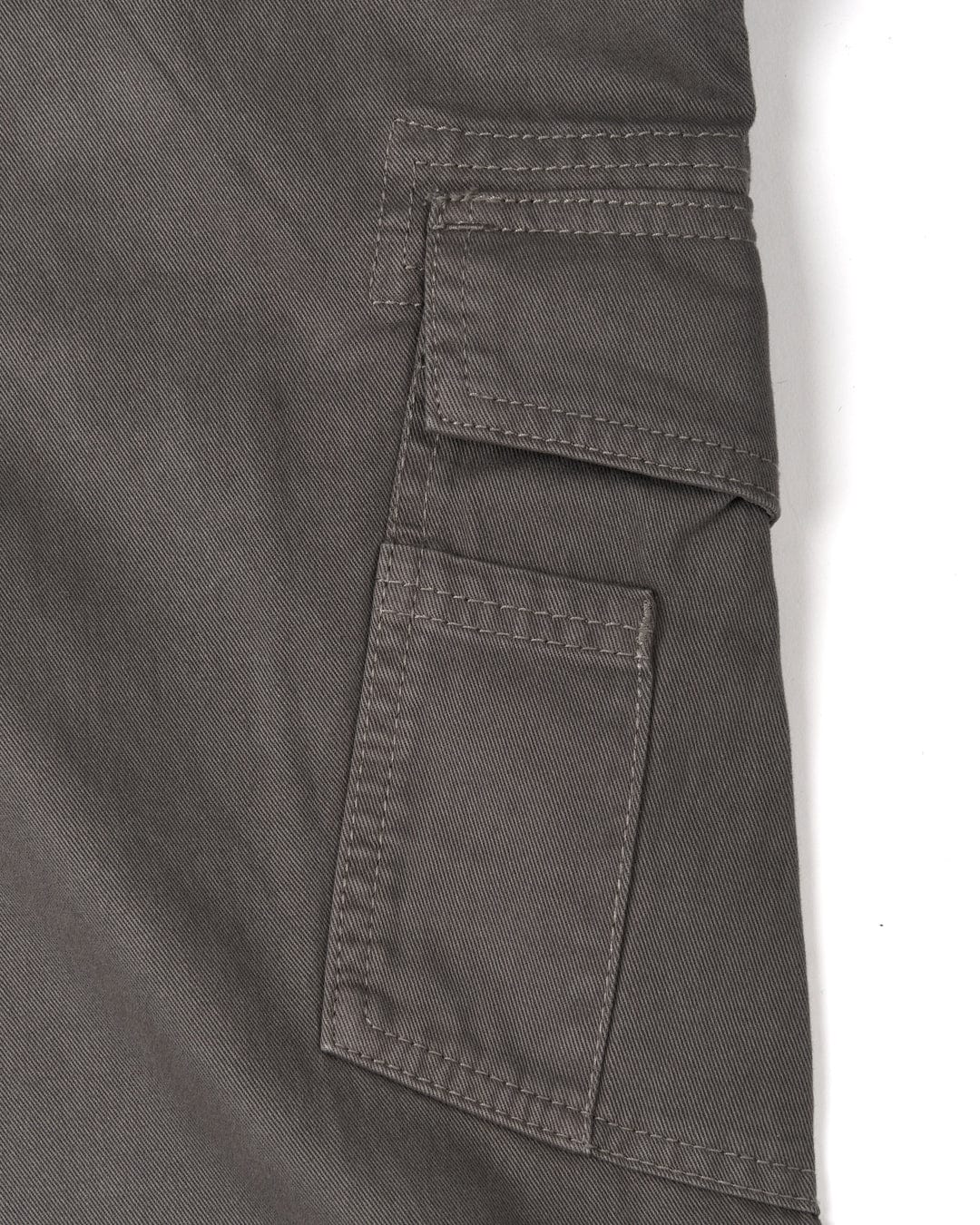 Close-up of a Saltrock Godrevy 2 - Mens Cargo Trousers - Dark Grey with cargo patch pockets and a pocket detail.
