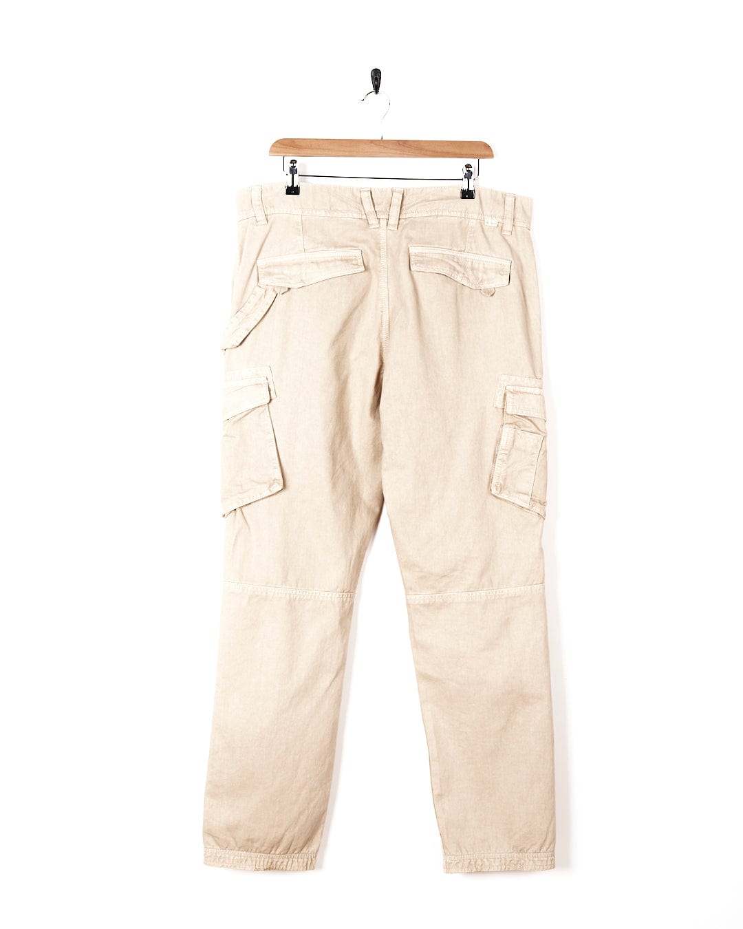 A pair of Saltrock Godrevy - Mens Cargo Trouser - Sand hanging on a hanger.