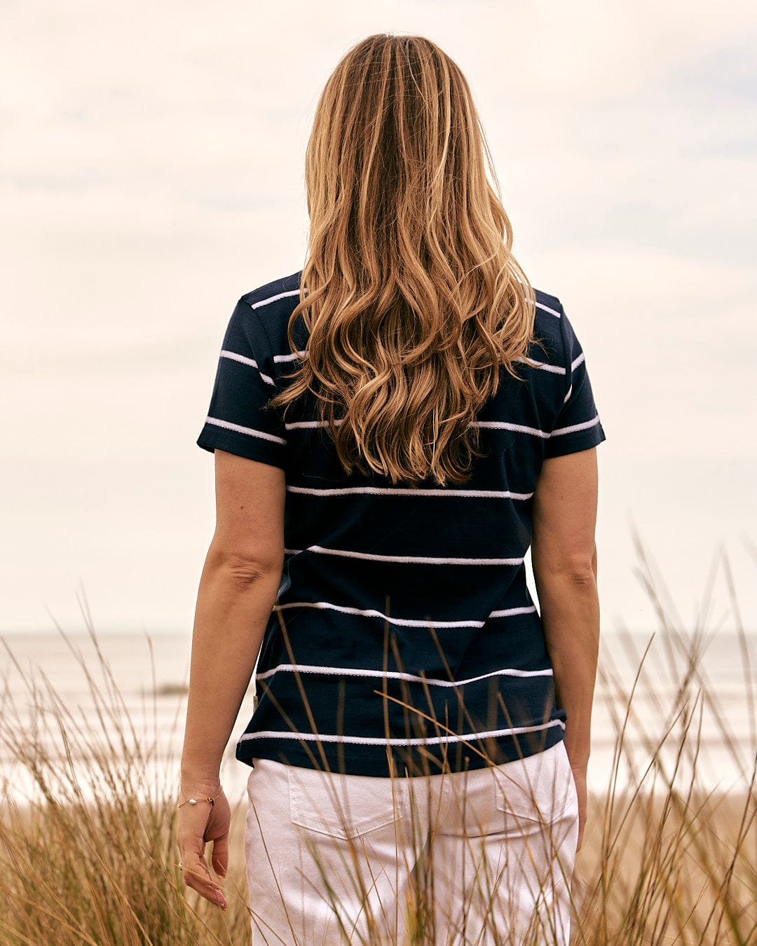 The Saltrock - Womens Striped Short Sleeve T-Shirt - Blue worn by a woman looking at the ocean.