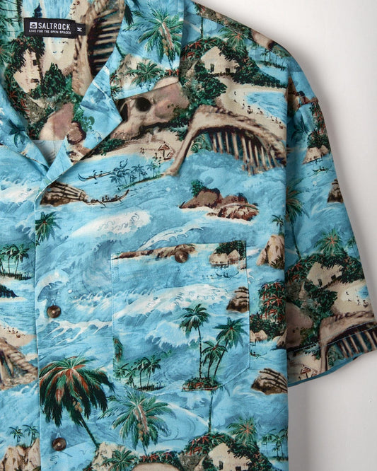 Close-up of a Saltrock Hawaiian Isle - Mens Short Sleeve Shirt - Blue with tropical landscape print, featuring palm trees, islands, and ocean waves.
