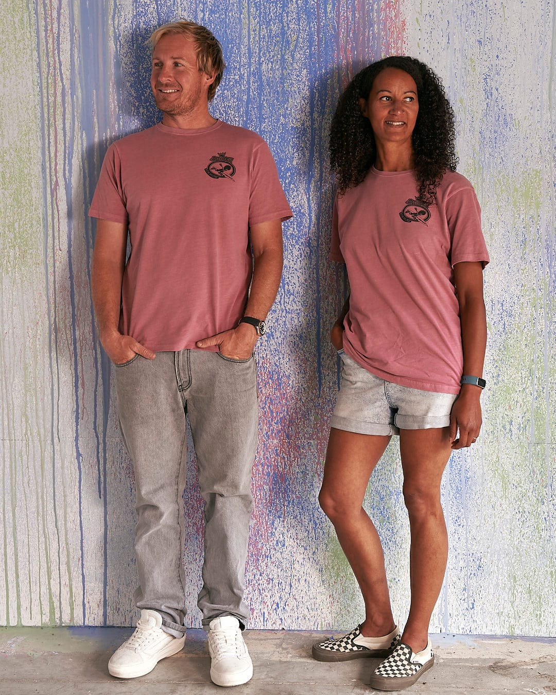 A man and woman standing next to each other wearing Saltrock's Heraldic Tok - Limited Edition 35 Years T-Shirts.