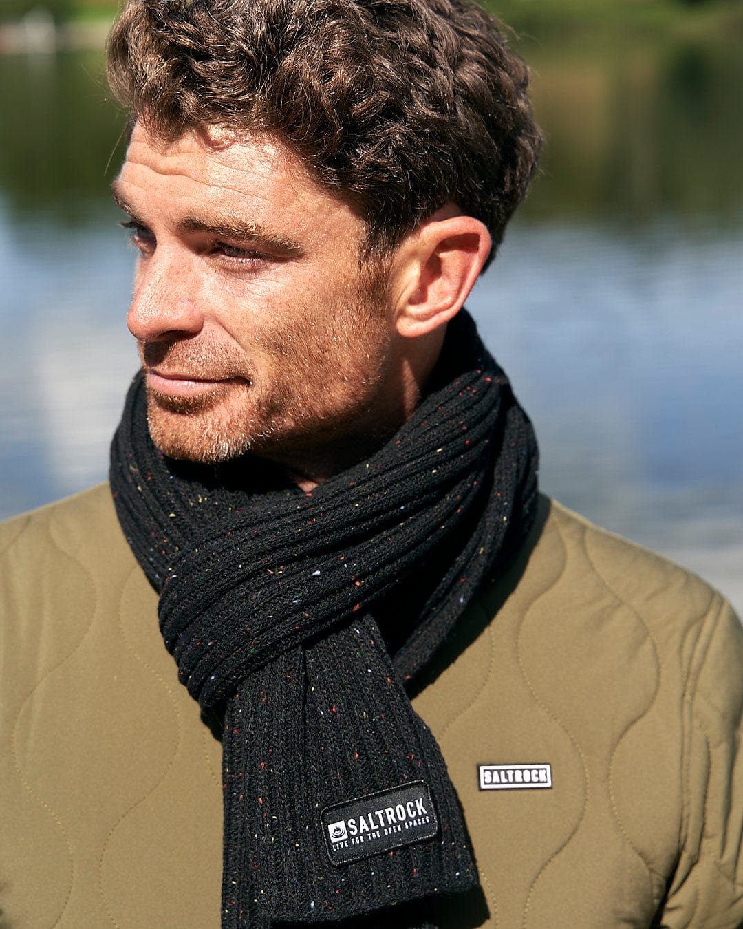 A man in a green jacket, wearing a Saltrock Heritage Scarf in black for extra warmth.