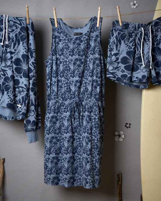 Saltrock's Blue floral-printed dress, the Hibiscus Bauhaus - Womens Midi Dress - Blue, is hanging on a clothesline with other garments against a beige wall.