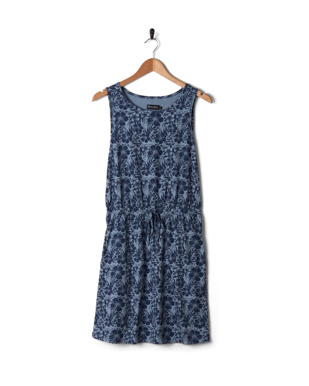 Blue floral dress featuring Hibiscus Bauhaus, hanging on a wooden hanger against a white background. Brand: Saltrock