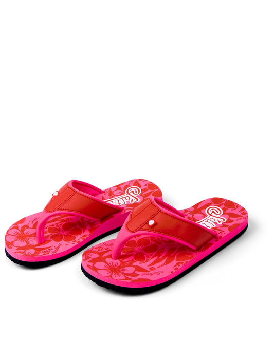 A pair of pink flip-flops with a Saltrock Hibiscus pattern on the soles, isolated on a white background.