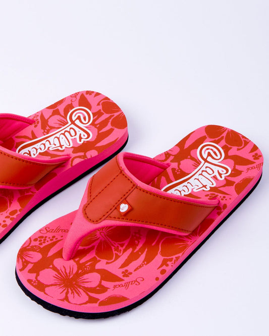 A pair of pink Saltrock Hibiscus-patterned sandals with the Saltrock branding displayed on the strap, set against a white background.