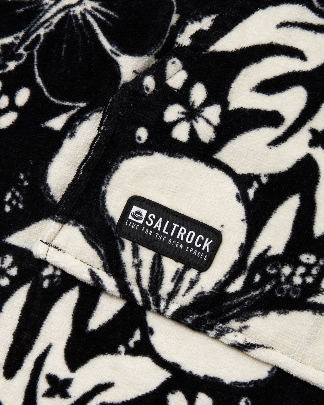 Close-up of a black and white patterned ultra-absorbent "Hibiscus" changing towel with a "Saltrock" brand label.