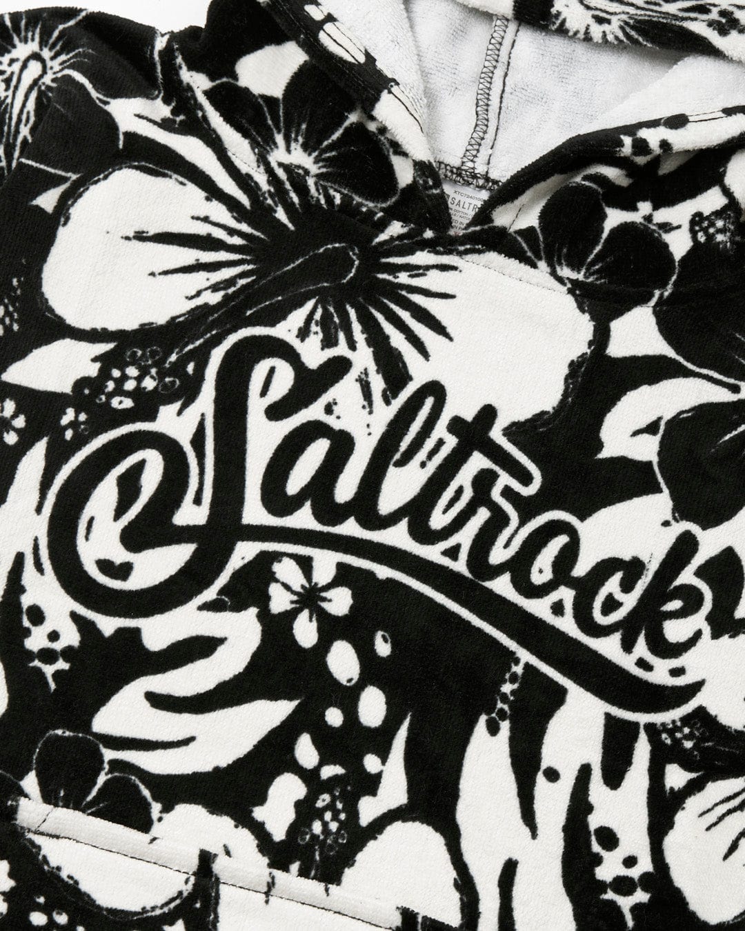 Close-up of an ultra-absorbent Hibiscus - Kids Changing Towel - Black/White with the word "Saltrock" scripted across the front.