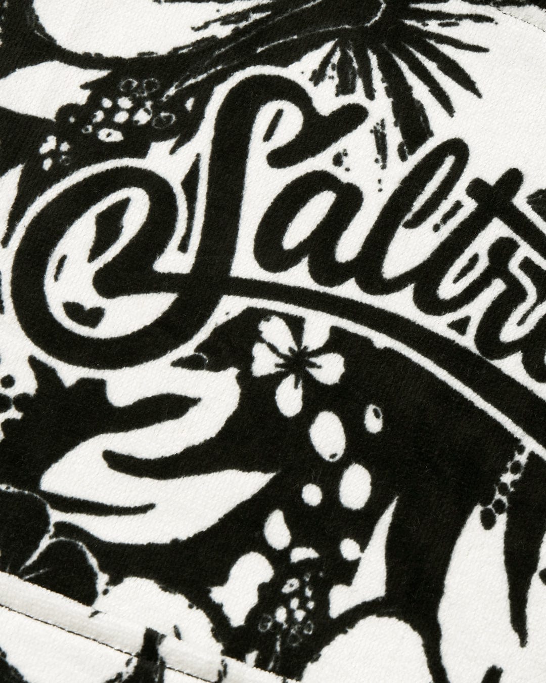 Close-up of a black and white 100% cotton Hibiscus - Kids Changing Towel by Saltrock with a floral design and the word 