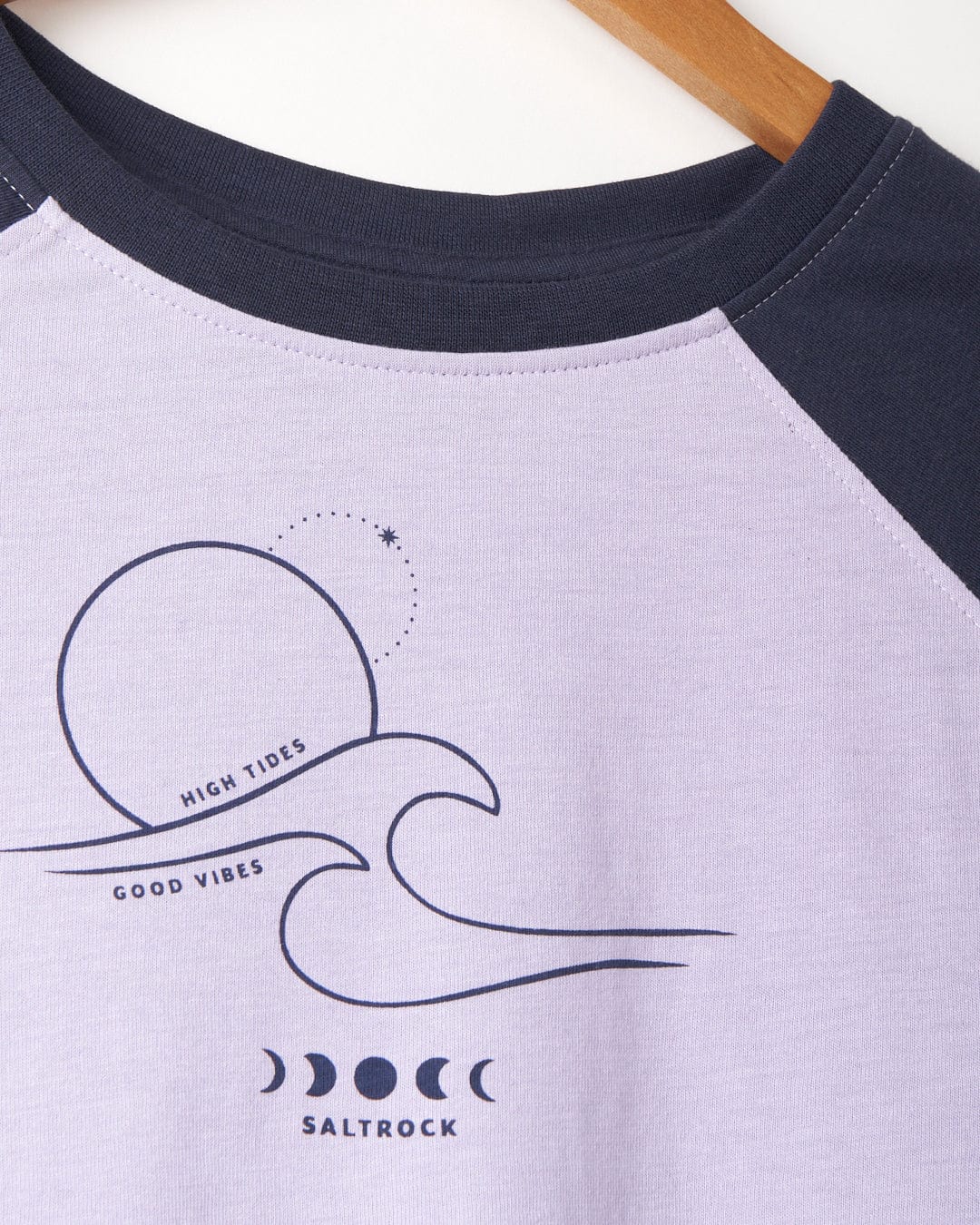A Saltrock High Tides - Womens Raglan Long Sleeve T-Shirt - Light Purple featuring a moon and waves design, with a high tides graphic for a peached soft hand feel finish.