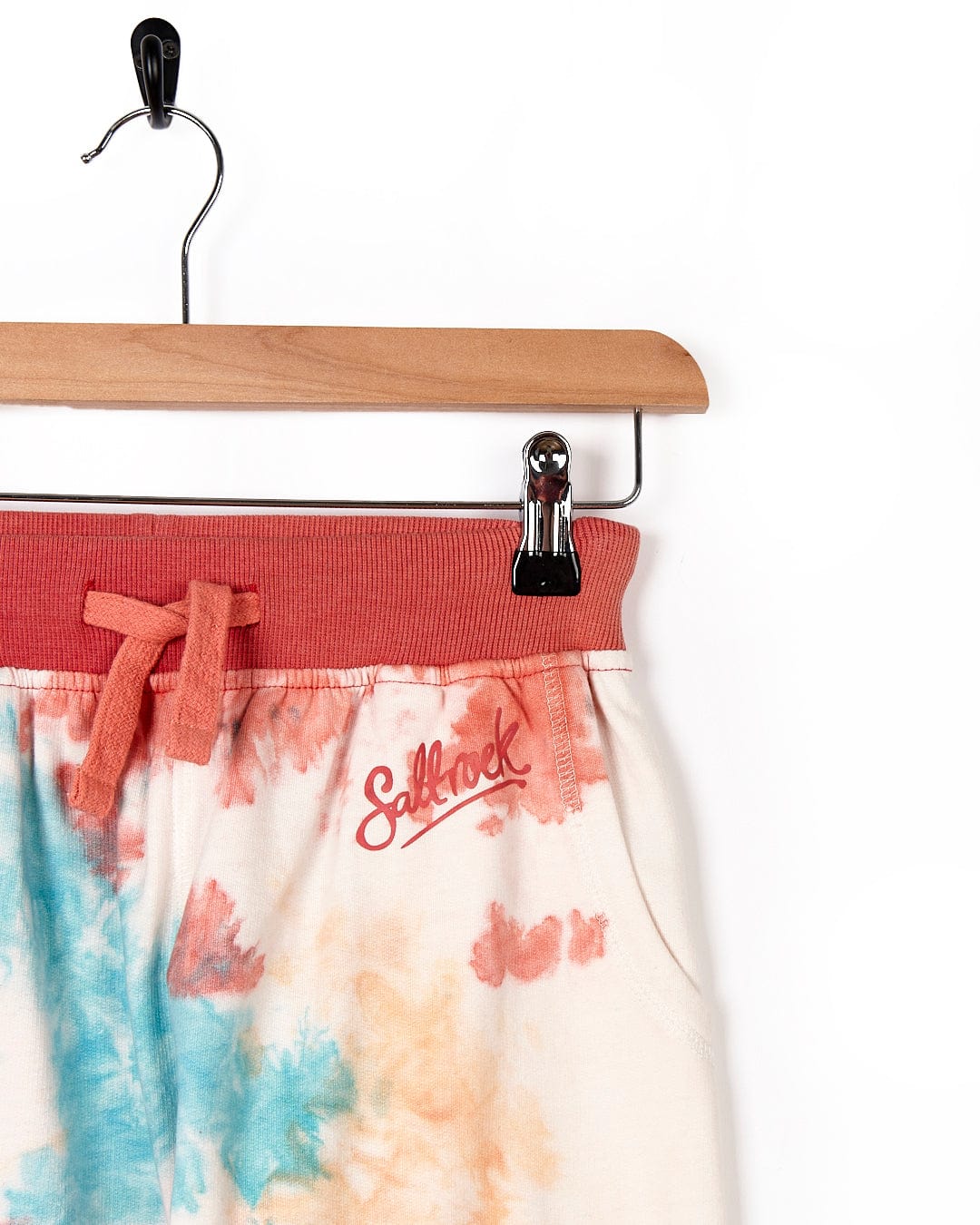 A pair of Saltrock Hippy - Kids Tie Dye Jogger - Multi shorts hanging on a hanger.