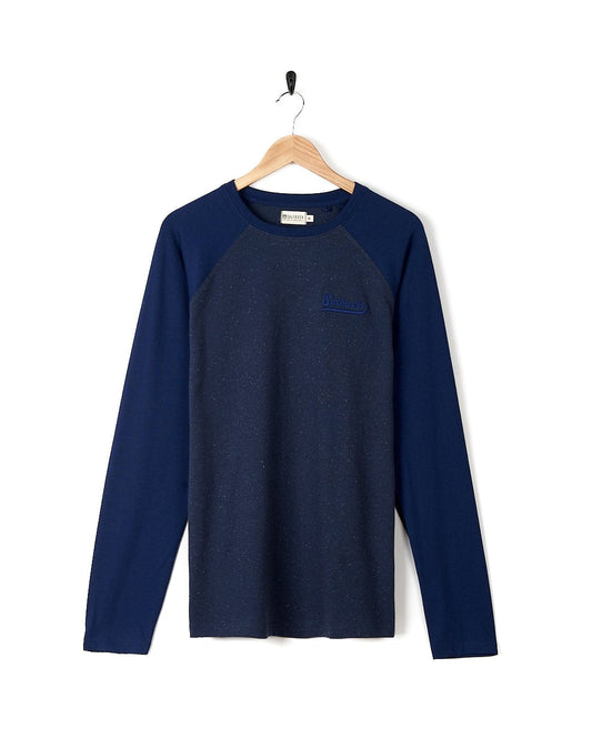 The men's navy Home Run Nep - Mens Raglan Long Sleeve T-Shirt - Blue is hanging on a hanger. Brand: Saltrock