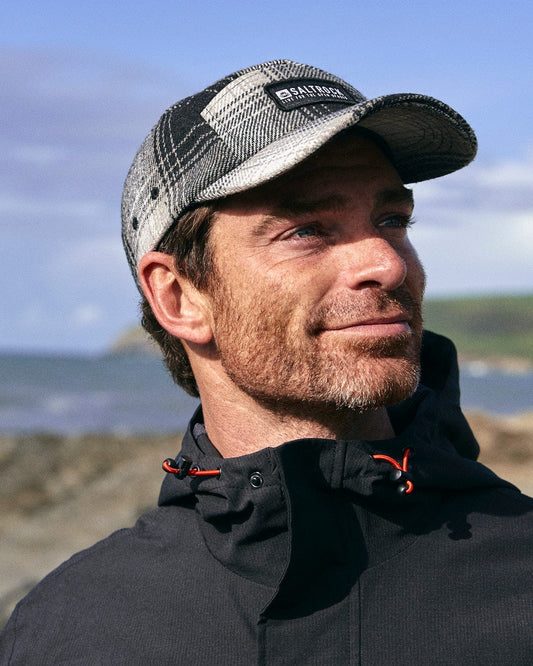 A Saltrock branding man in a Hunter - 5 Panel Cap - Grey on the beach.