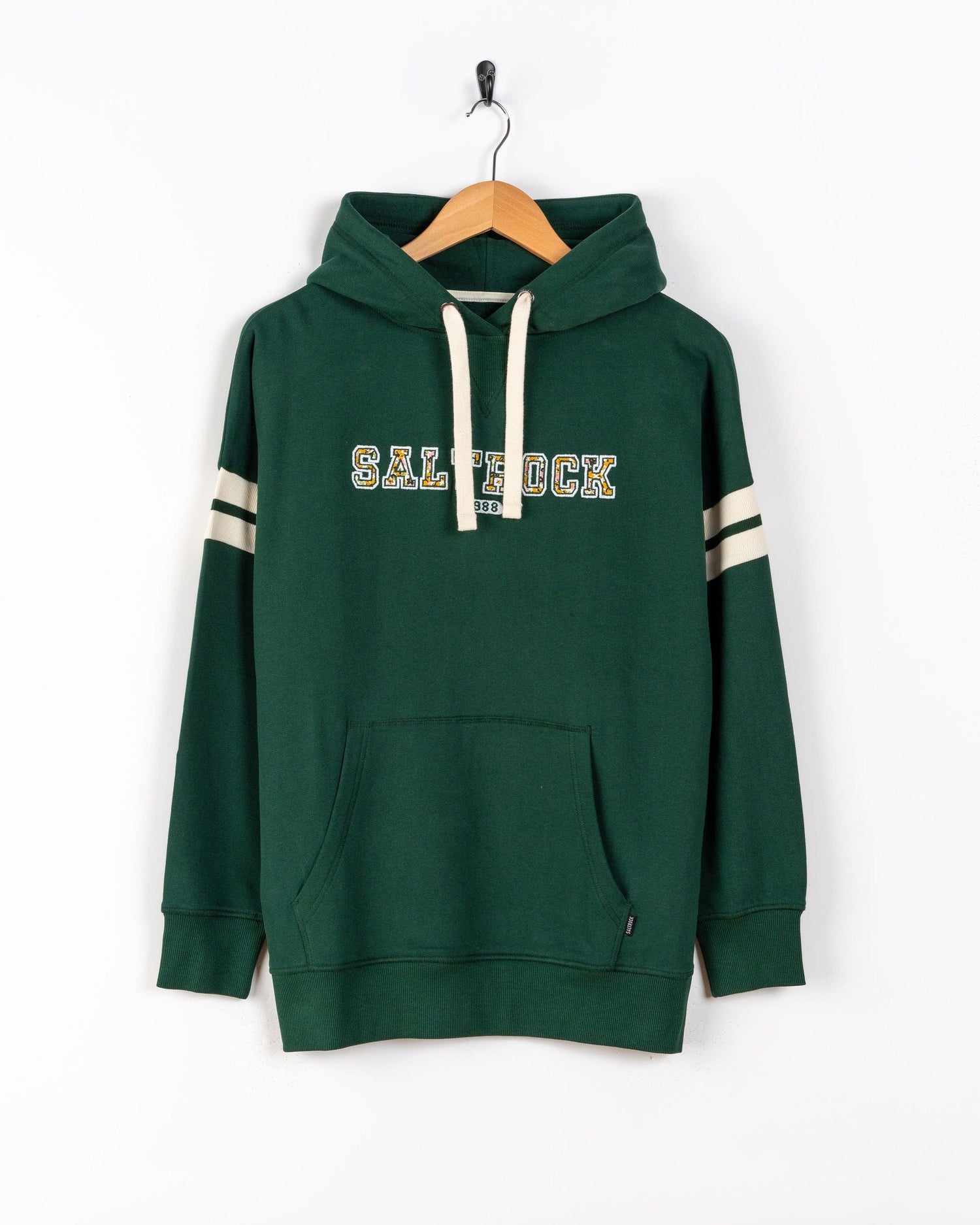 The Saltrock Campus Floral Women's Pop Hoodie in dark green, made from 100% cotton, features white drawstrings, a front pocket, and "SALTROCK" on the chest. Shown on a hanger against a white background.