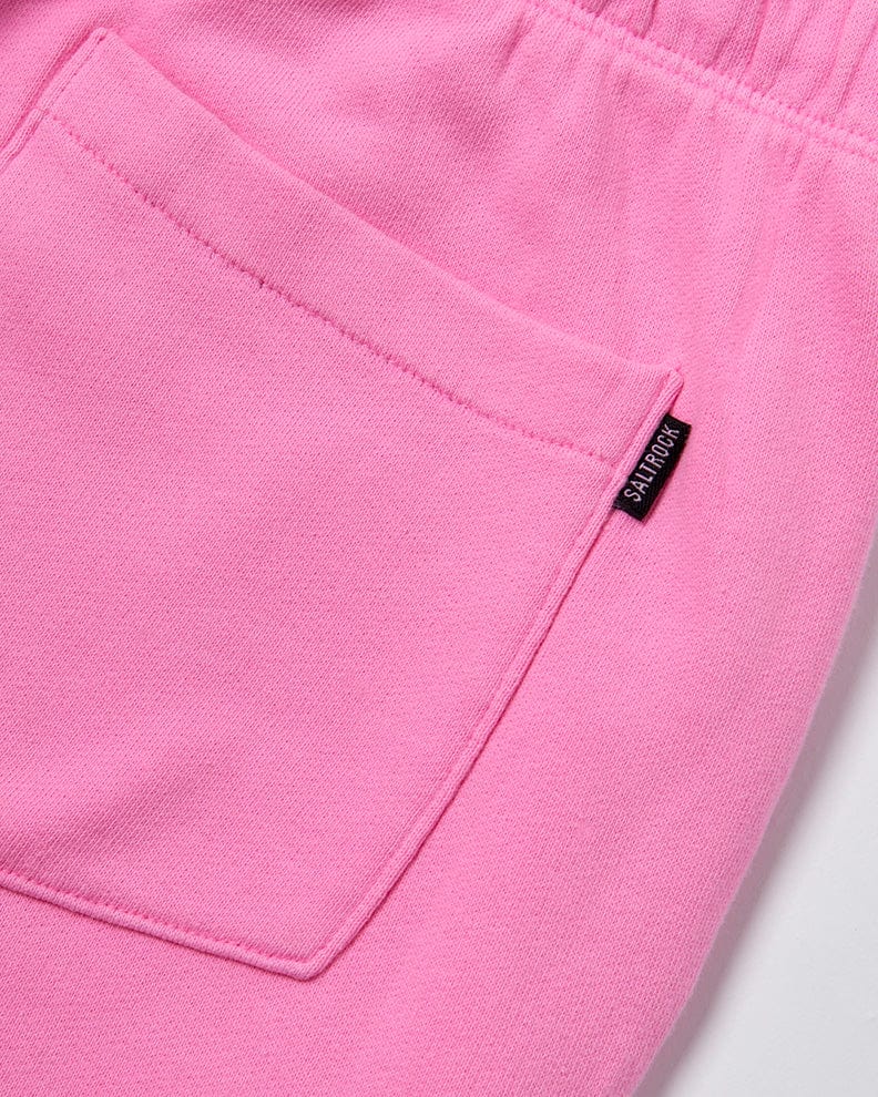 Close-up of a pink fabric with a focus on the pocket detail, featuring a small black label with the word "Instow - Womens Jogging Bottom - Pink" in white text by Saltrock.
