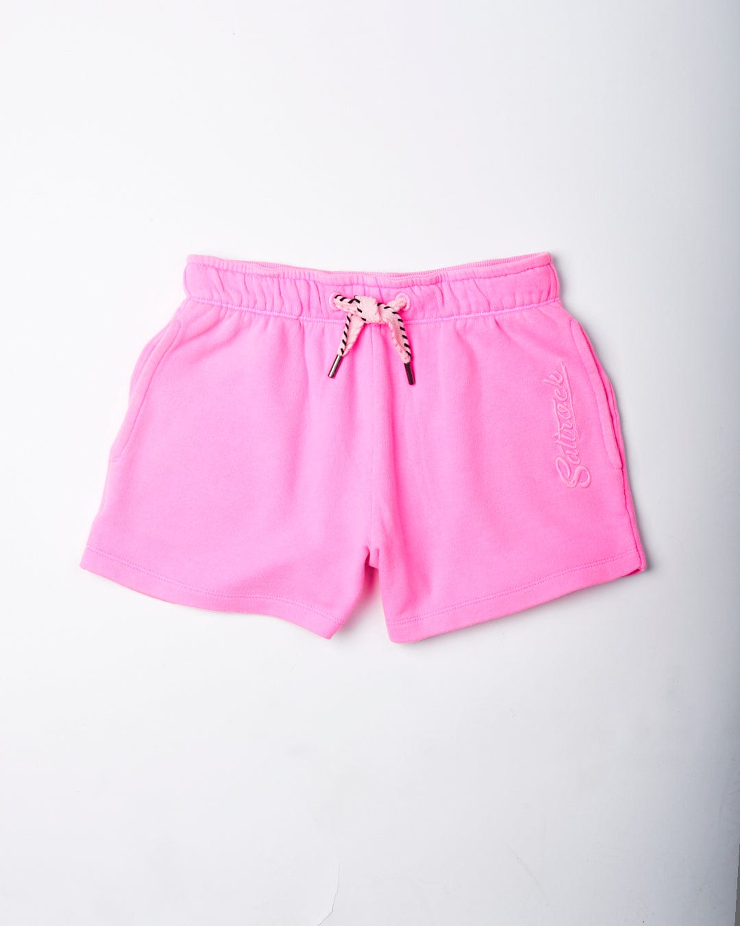 Bright pink Instow Kids Sweat Shorts with an elasticated waist and cursive embroidery on the left leg displayed on a white background by Saltrock.