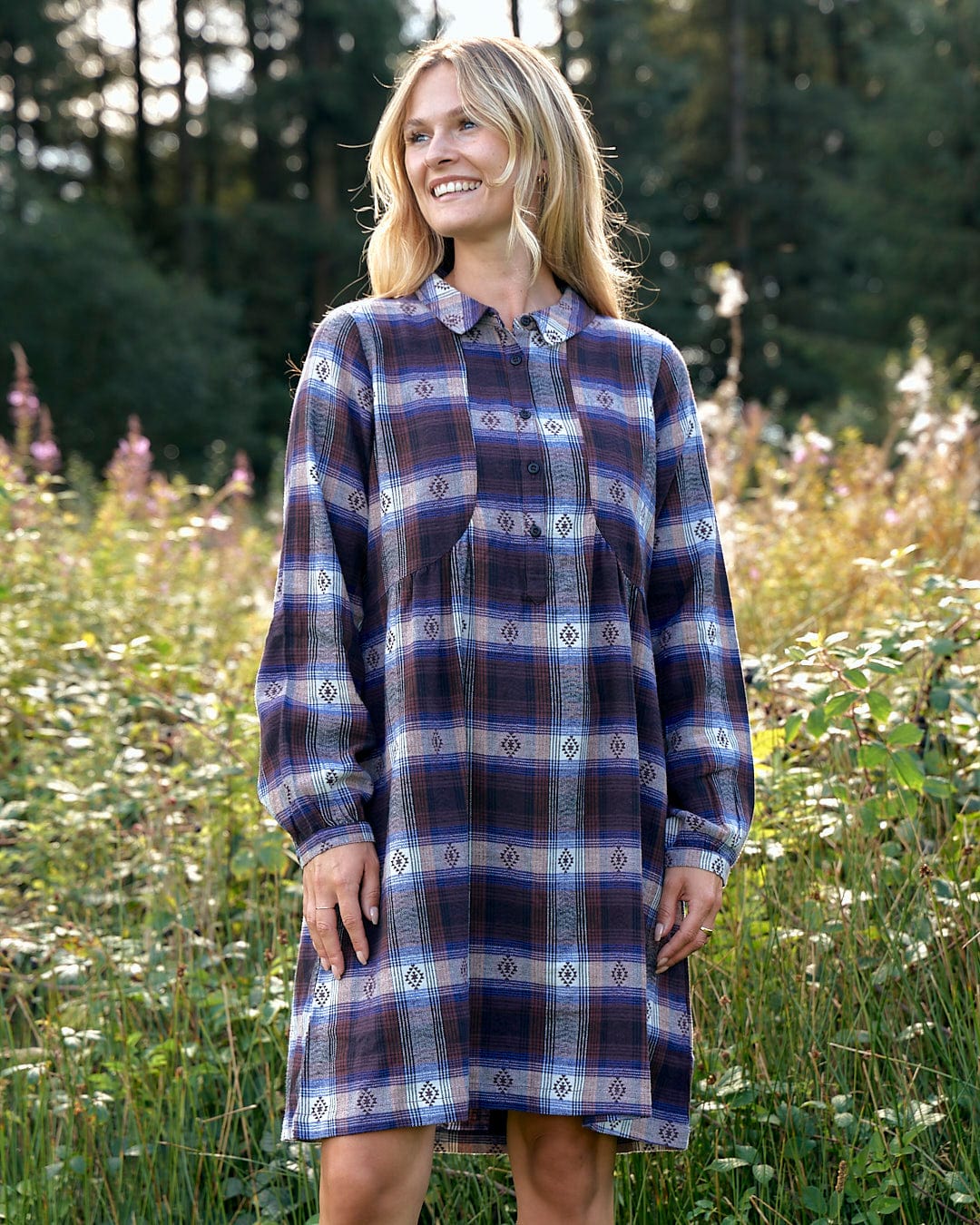 A woman in the Saltrock Ivy - Womens Jacquard Check Shirt Dress - Purple with a flattering silhouette standing in a field.