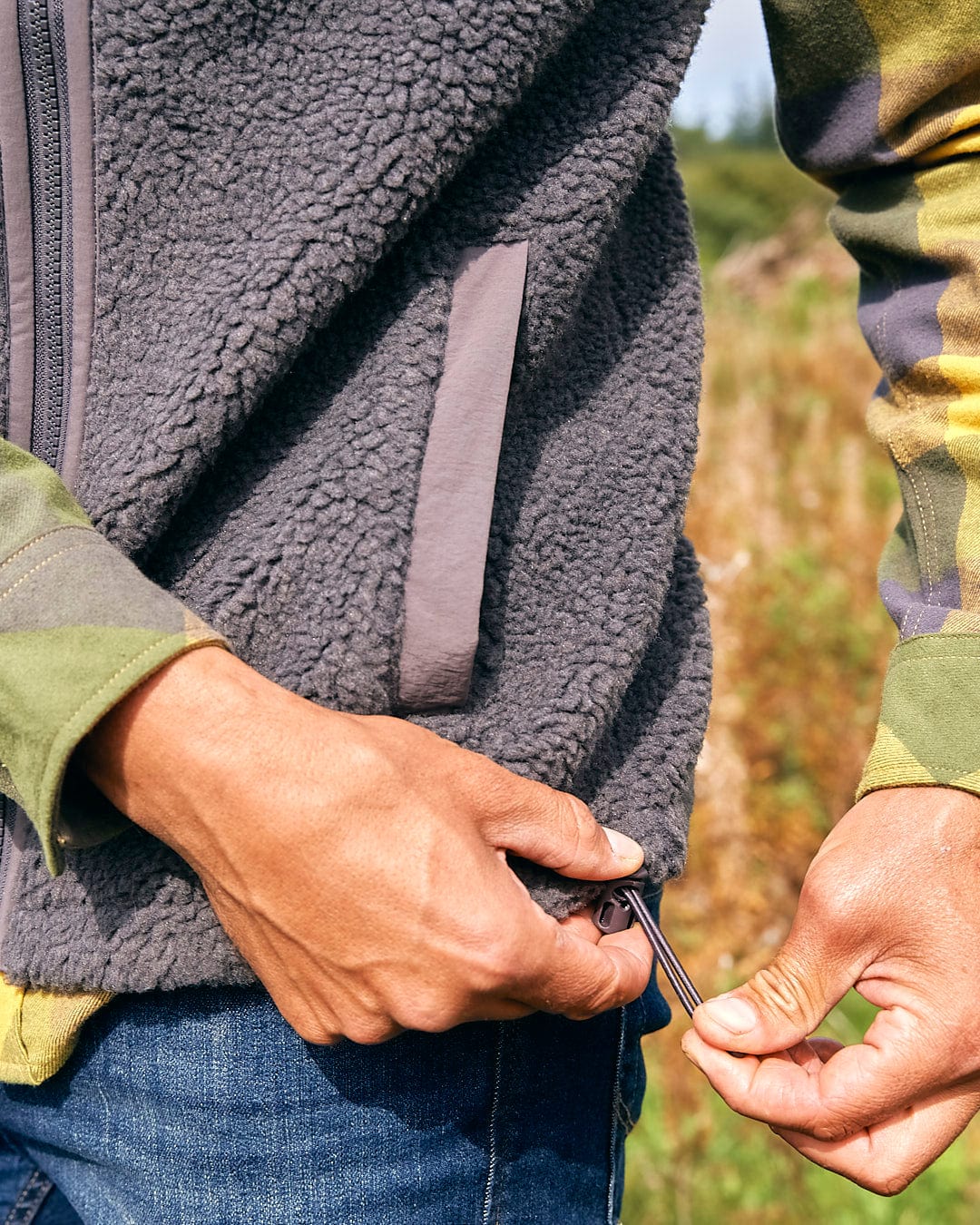 A man is holding a Joel - Mens Sherpa Fleece Gilet - Dark Grey by Saltrock in his jacket.