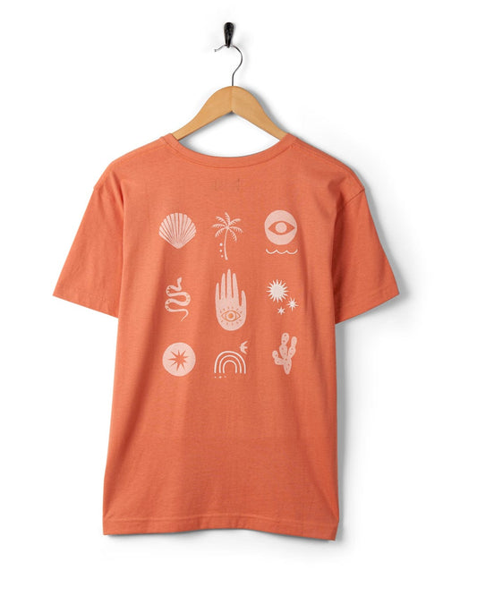 Journey - Recycled Womens Short Sleeve T-Shirt - Peach by Saltrock with white bohemian symbols embroidered on recycled polyester, hanging on a wall-mounted hook against a white background.