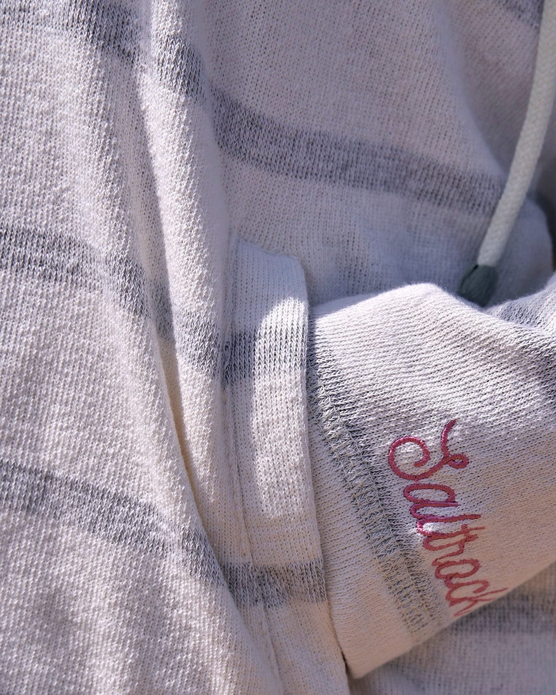 A woman wearing a Kennedy - Womens Pop Hoodie - Cream with pink lettering from Saltrock.