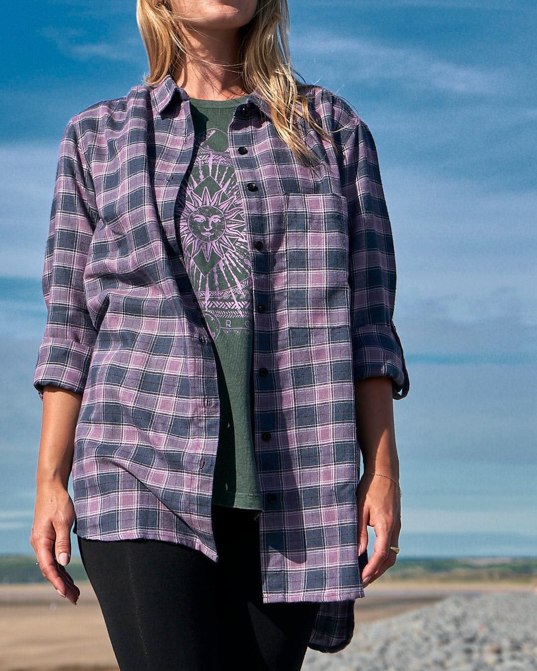 A woman wearing a Saltrock Kizzie Womens Check Boyfriend Shirt - Purple standing on a beach.
